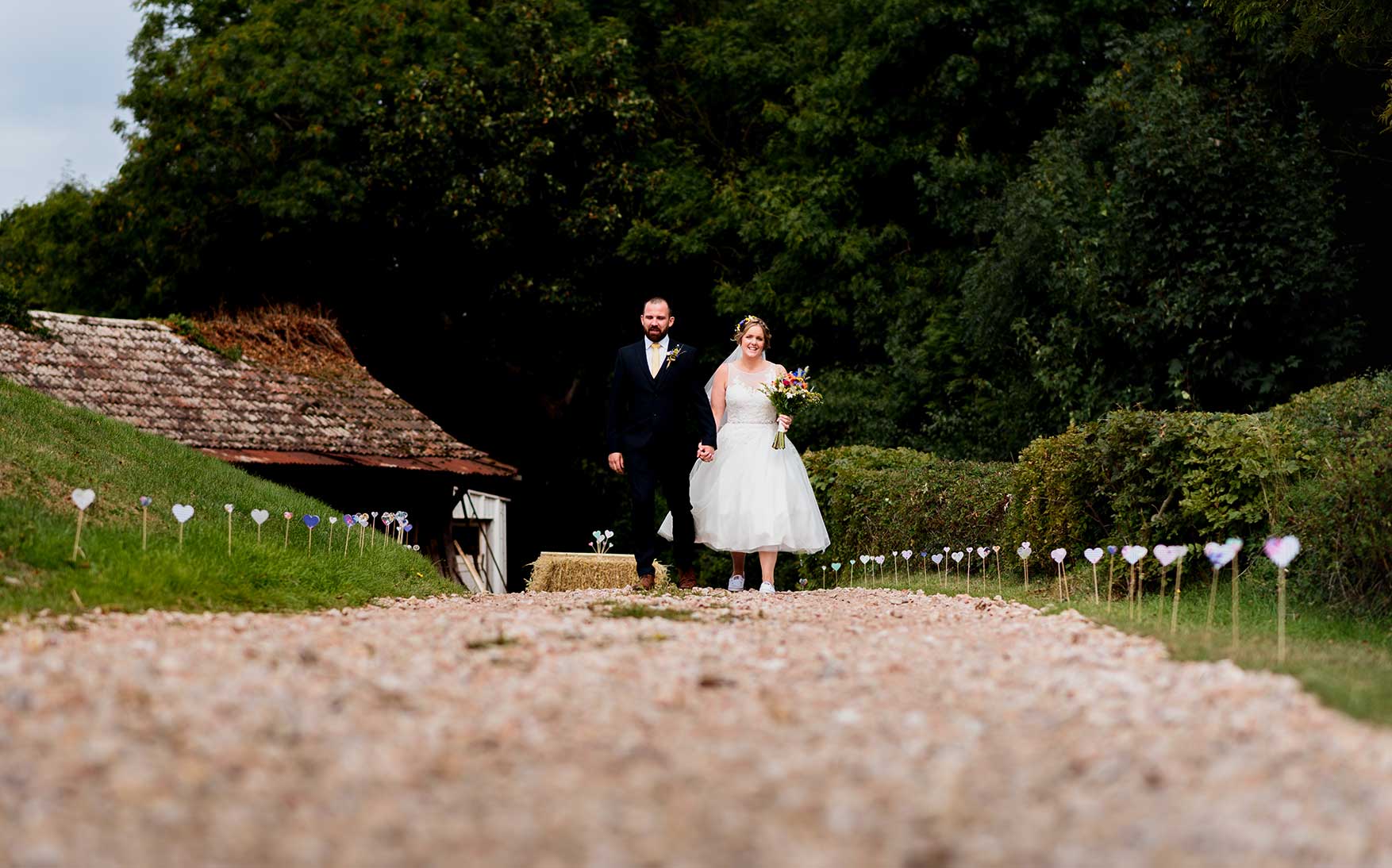 Bride and groom walking down path to the barn